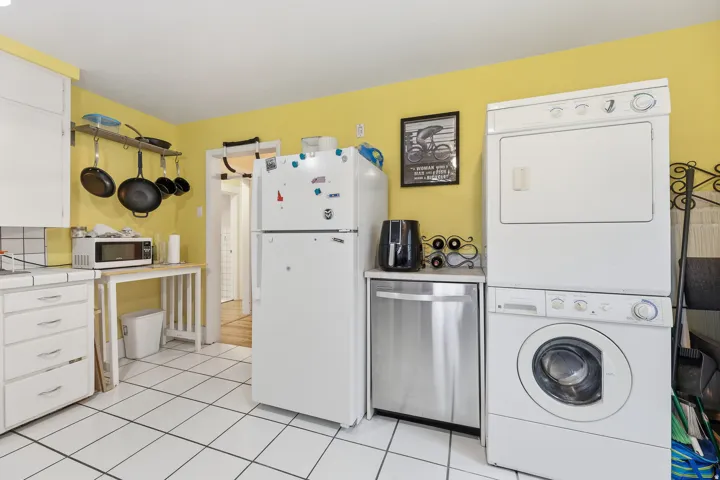 Kitchen with white cabinetry, tile flooring, a white refrigerator, and a stainless steel dishwasher
