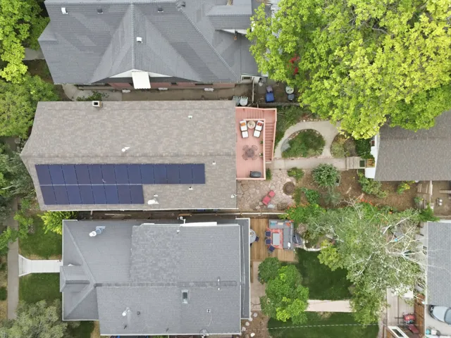 Residential property featuring a large rooftop solar array and a two-tiered wooden deck