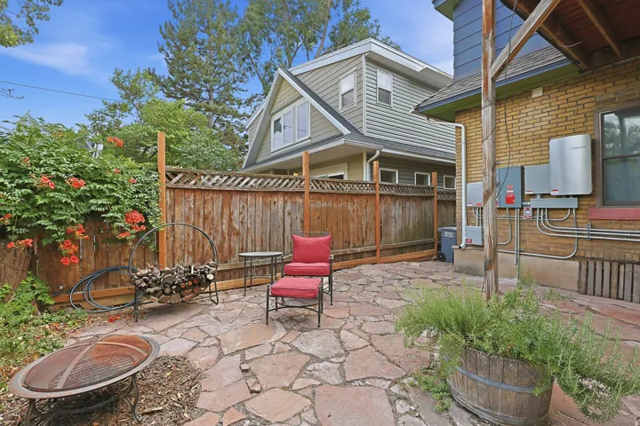 Stone patio area featuring a fire pit, privacy fencing, and a brick exterior