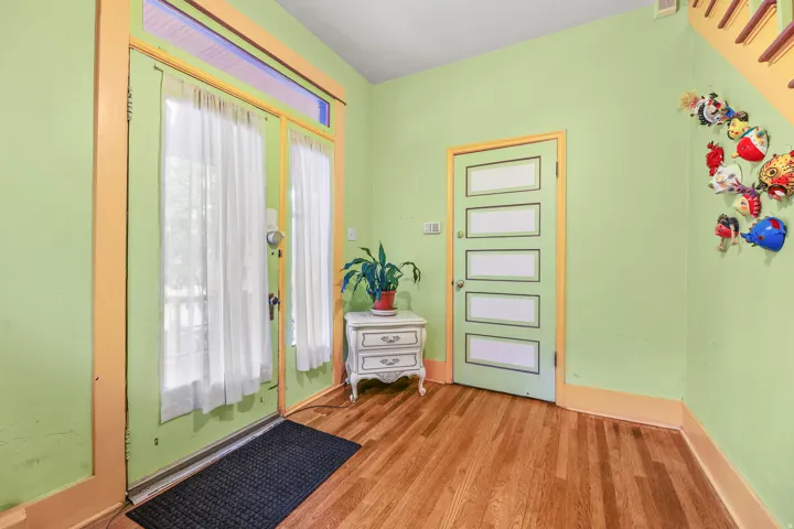 Entryway featuring wood-finish flooring, a glass-paneled entry door with transom window, and a panel door with multiple horizontal glass inserts