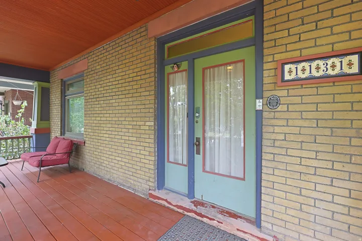 Front porch entrance featuring a solid wood door with glass inserts, transom window, and a brick exterior