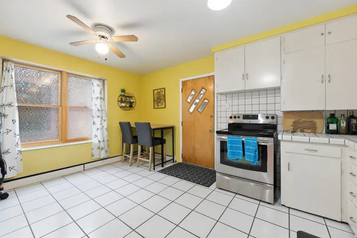 Kitchen featuring white square tile flooring, white cabinetry, and a stainless steel electric range