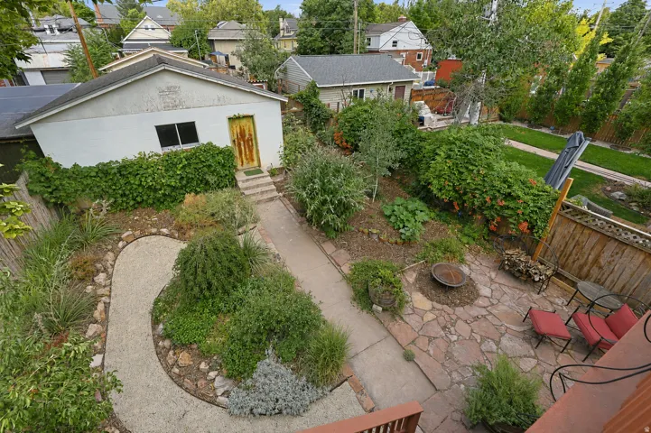 Landscaped backyard featuring a stone patio, an informal gravel path, a fire pit area, and mature plantings