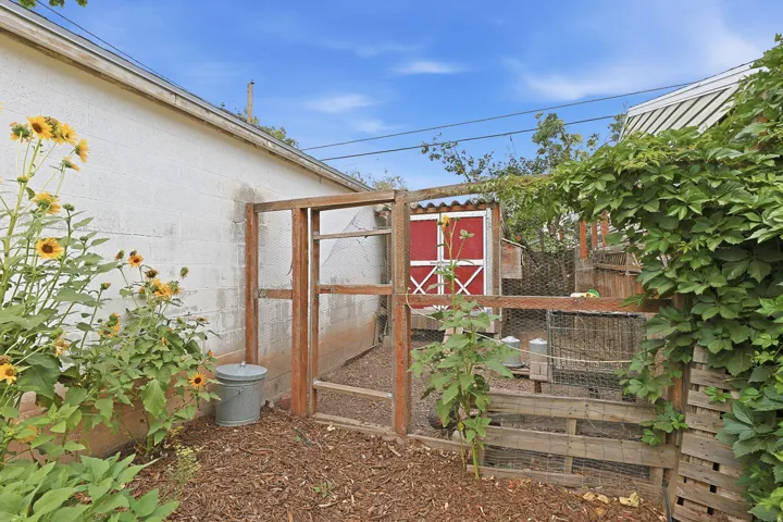 Outdoor structure with red-painted door and white trim, surrounded by wood fencing and wire mesh