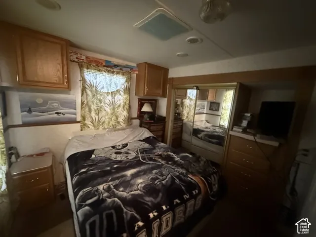 Built-in cabinetry, overhead lighting, window with drapes, mirrored closet doors, and wood-finish drawer storage