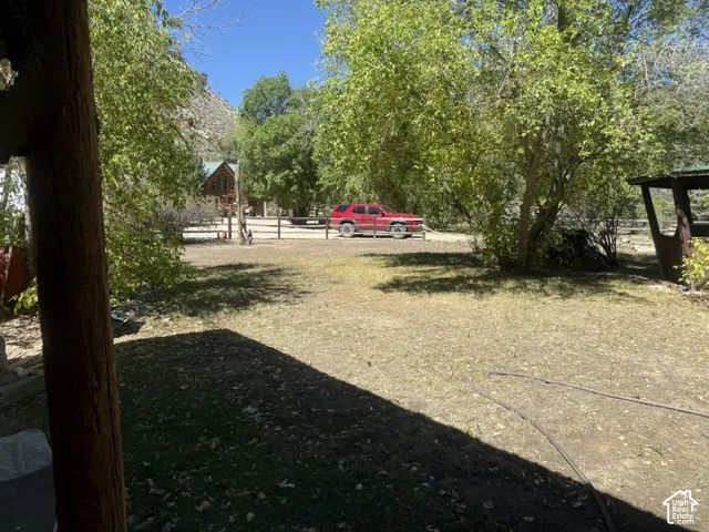 Expansive outdoor area featuring a rustic wood-post structure, mature trees, and natural landscaping