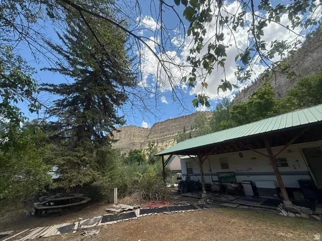 Expansive covered patio extending the length of the residence, featuring a pitched green metal roof and wood support posts