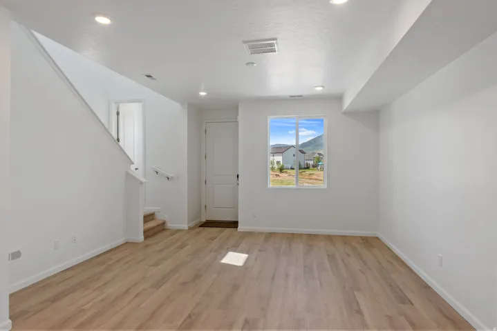 Open-concept living area featuring wood-finish flooring, recessed lighting, and a white interior paint scheme