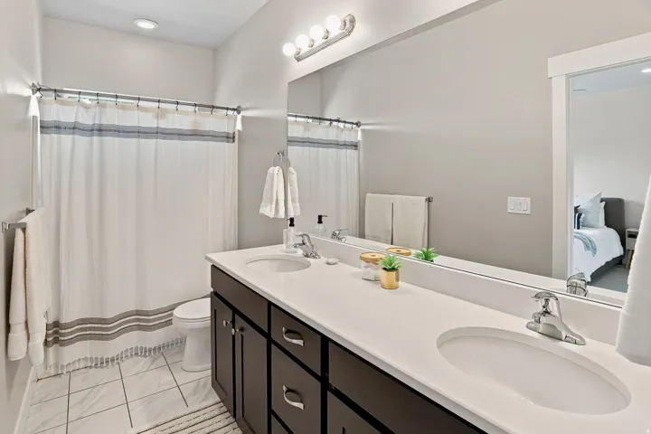 Dual vanity with integrated sinks, dark wood-finish cabinetry, and a full-width mirror