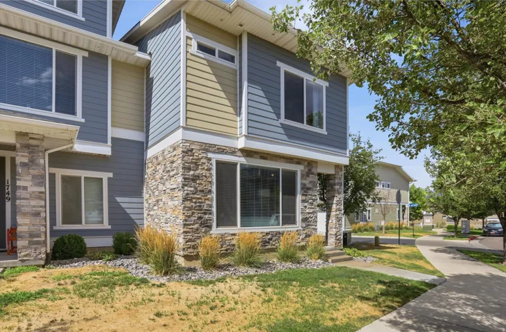 Multi-level exterior featuring blue horizontal siding, tan horizontal siding, stacked stone accents, and white trim