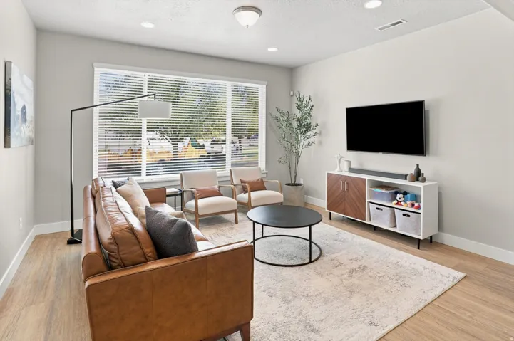 Living area featuring light wood-finish flooring, recessed lighting, and a large window with horizontal blinds