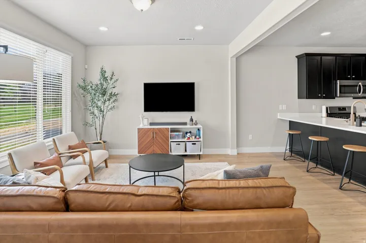 Open-concept living space featuring wood-finish flooring, recessed lighting, and large windows