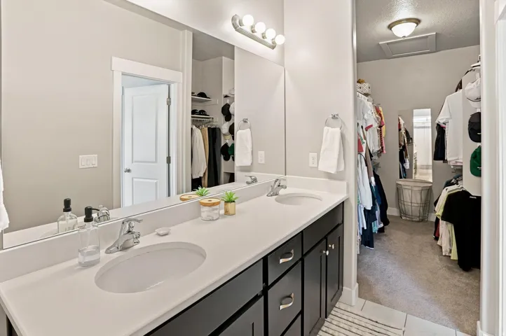 Bathroom with a dual-sink vanity featuring a light-colored countertop and dark cabinetry