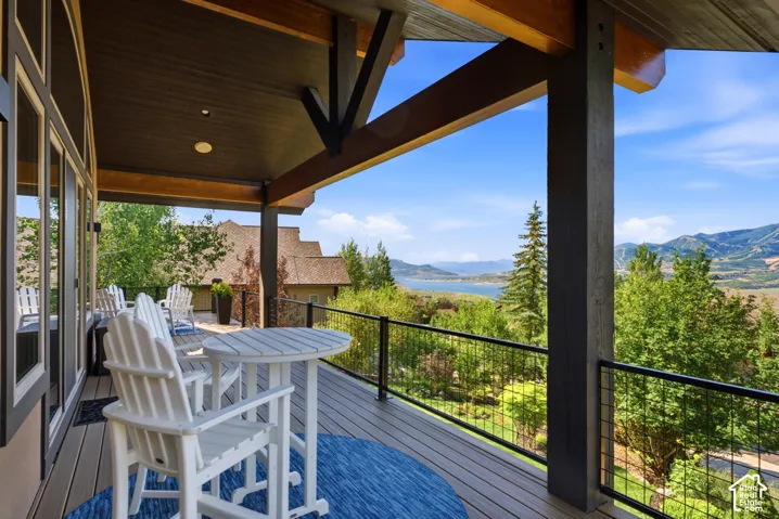 Expansive covered deck featuring composite decking, exposed wood beams, and metal railing