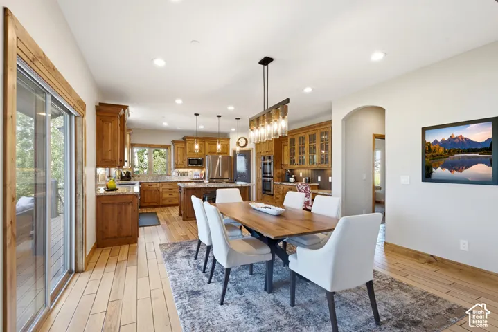 Open-concept dining area featuring wood-finish flooring, a contemporary linear chandelier, and recessed lighting