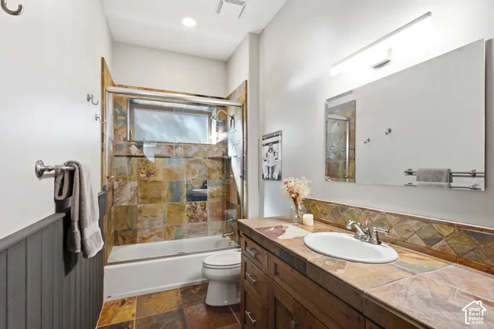 Bathroom featuring a slate tile floor and coordinating vanity countertop with a backsplash