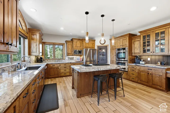 Spacious kitchen featuring extensive wood cabinetry, light-toned wood-finish flooring, and granite countertops
