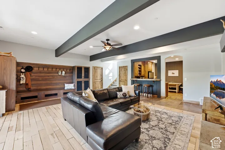 Spacious living area featuring light wood-finish flooring, recessed lighting, a built-in wood bench with storage, and a wet bar with seating