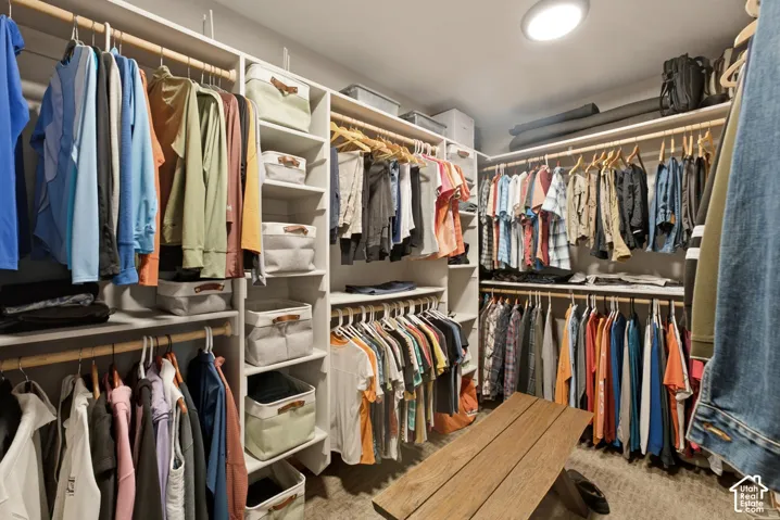 Custom-built closet system featuring extensive shelving, multiple hanging rods, corner storage, and a central wood-finish bench