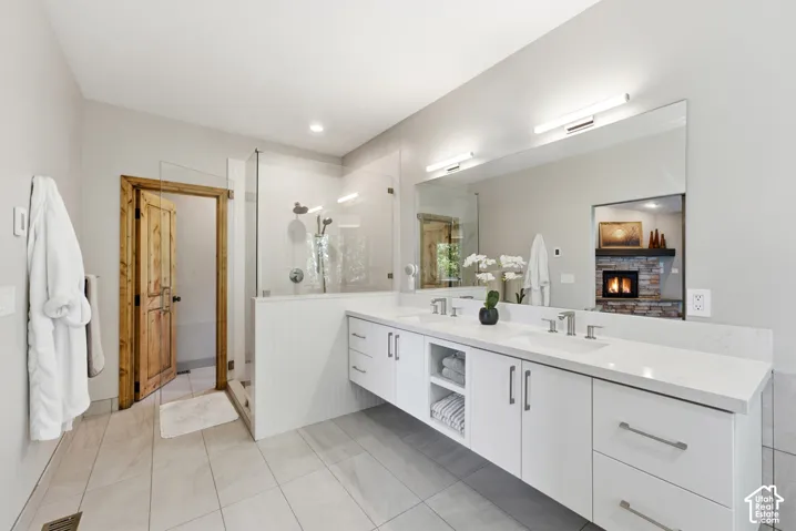 Bathroom featuring a dual vanity with white cabinetry, integrated sinks, and a large wall-mounted mirror