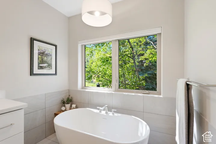 Freestanding soaking tub with chrome fixtures, complemented by large format wall tile