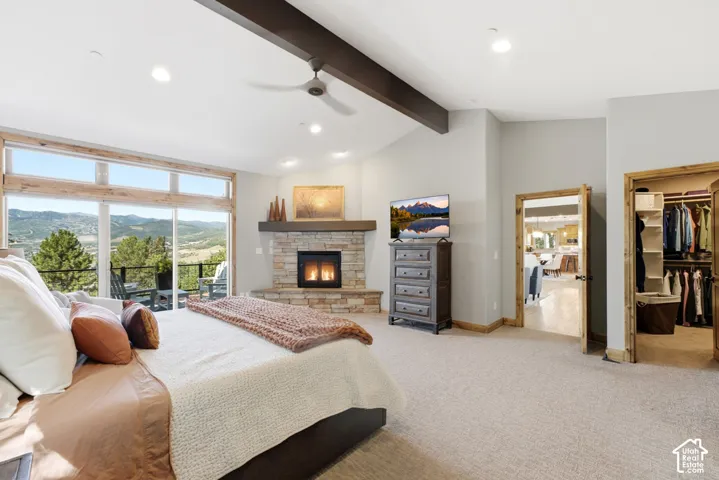 Vaulted ceilings with exposed beams, a stone-faced fireplace, and expansive glass sliding doors opening to a balcony