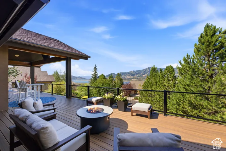 Expansive outdoor deck featuring wood-finish flooring, a contemporary fire pit, and a covered patio area