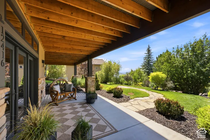 Covered patio featuring an exposed wood beam ceiling and stone pillar accents