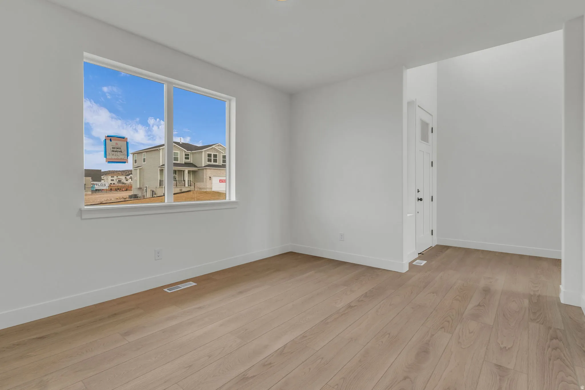 Bright interior office/flex space off entry way, featuring a large window.