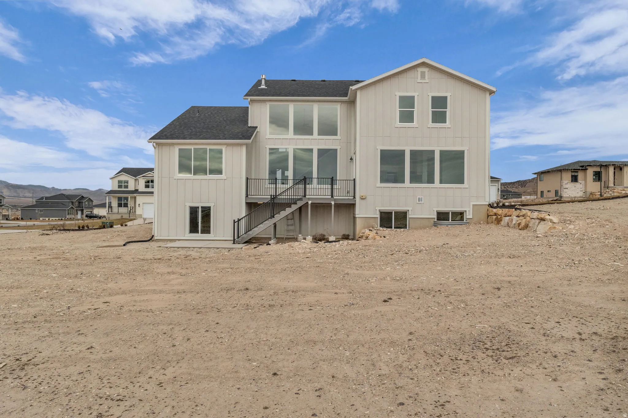 Exterior view of back of home showing large deck and covered porch areas and beautiful custom windows.