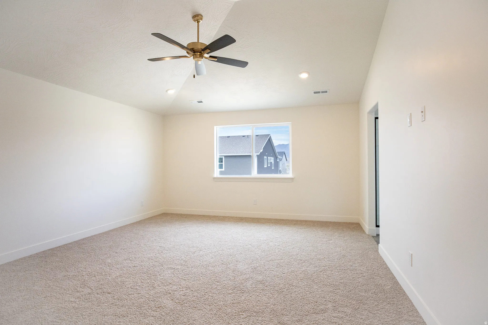 Terrific primary bedroom with vaulted ceiling and ceiling fan.