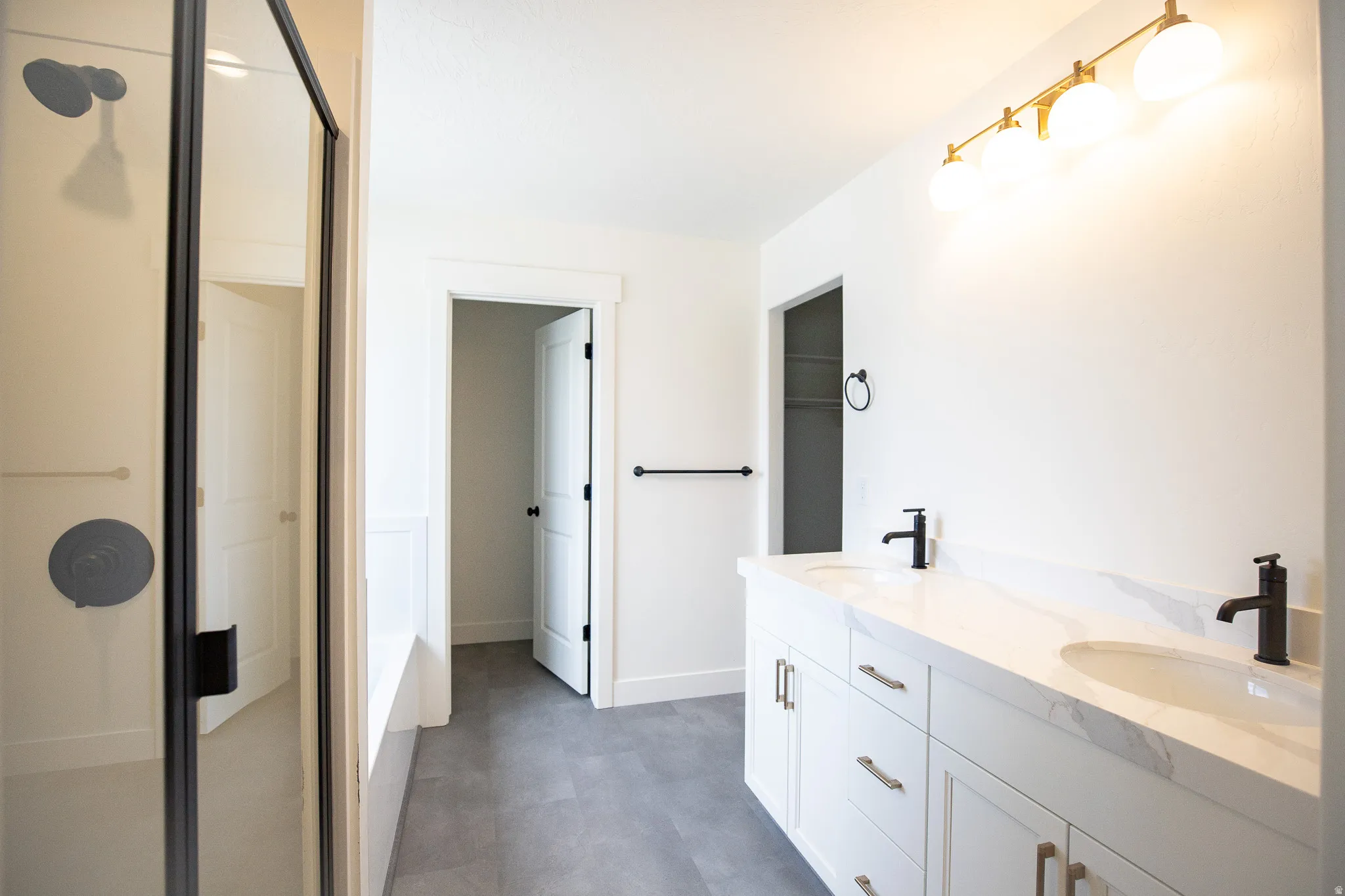Full primary bath with painted white wood cabinets, quartz slab countertops, large walk-in shower and soaker tub.
