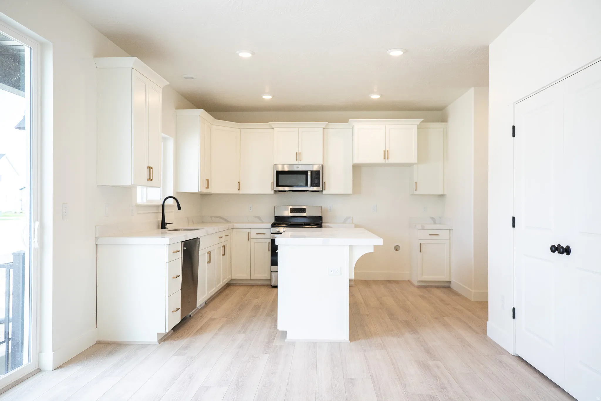 Kitchen with 42" uppers, painted white wood cabinets, quartz slab countertops, 6' island, gas range, dishwasher, disposal and microwave.