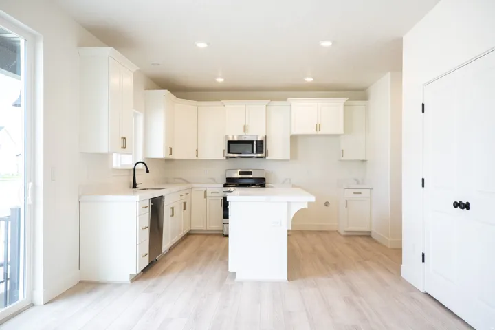 Kitchen with 42" uppers, painted white wood cabinets, quartz slab countertops, 6' island, gas range, dishwasher, disposal and microwave.