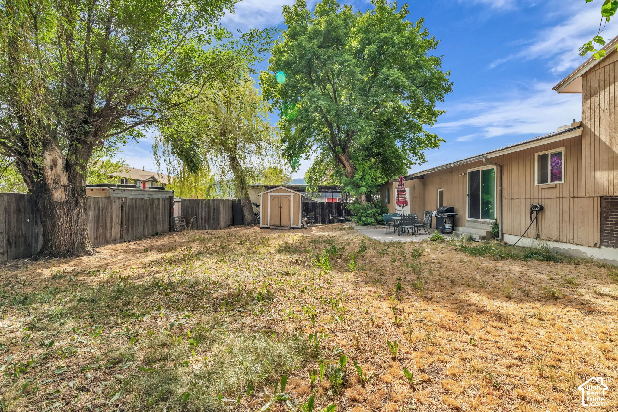 Spacious backyard featuring mature trees and a wood privacy fence