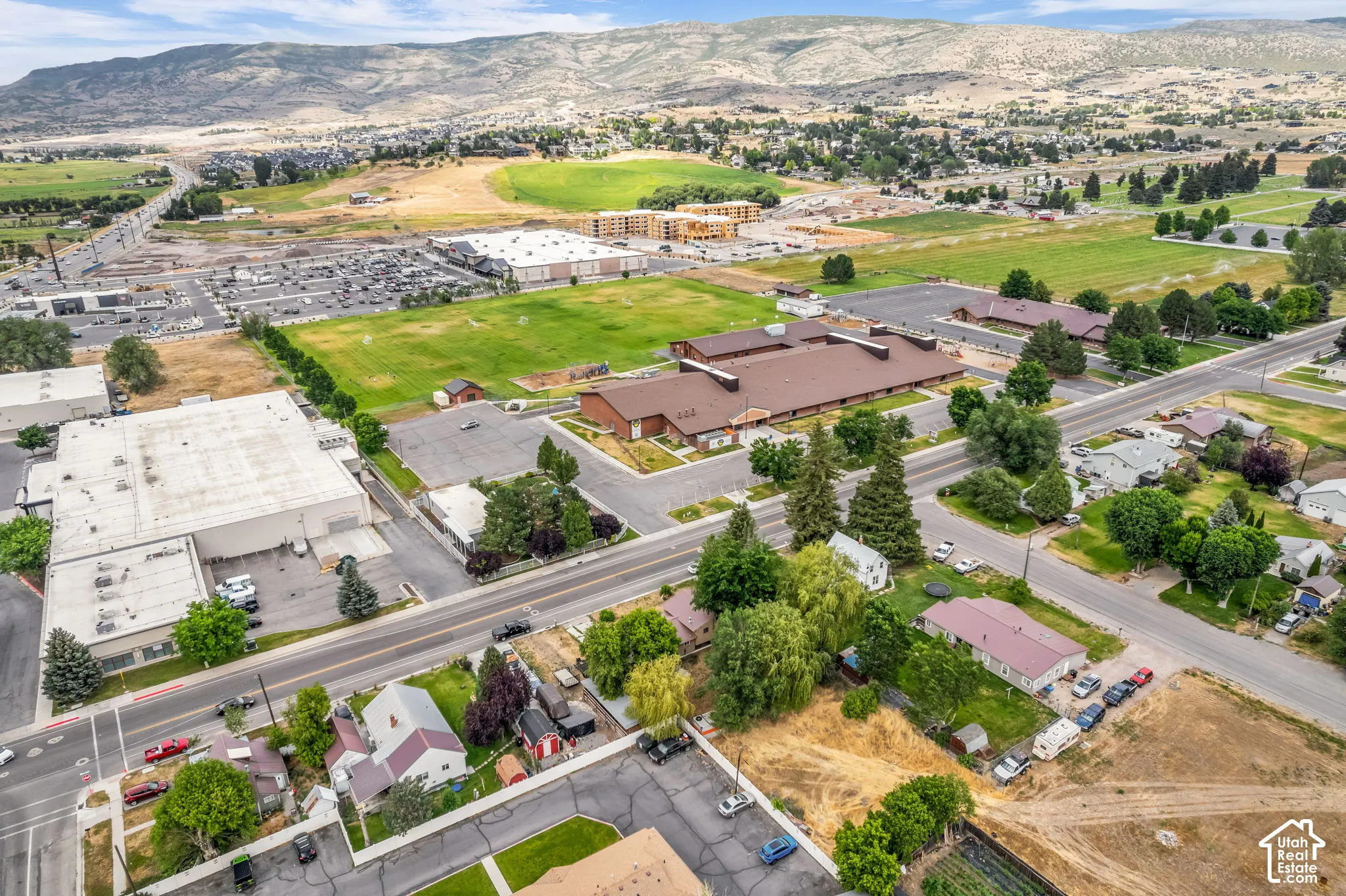 Expansive aerial perspective showcasing diverse property types, surrounding green spaces, and a mountain backdrop