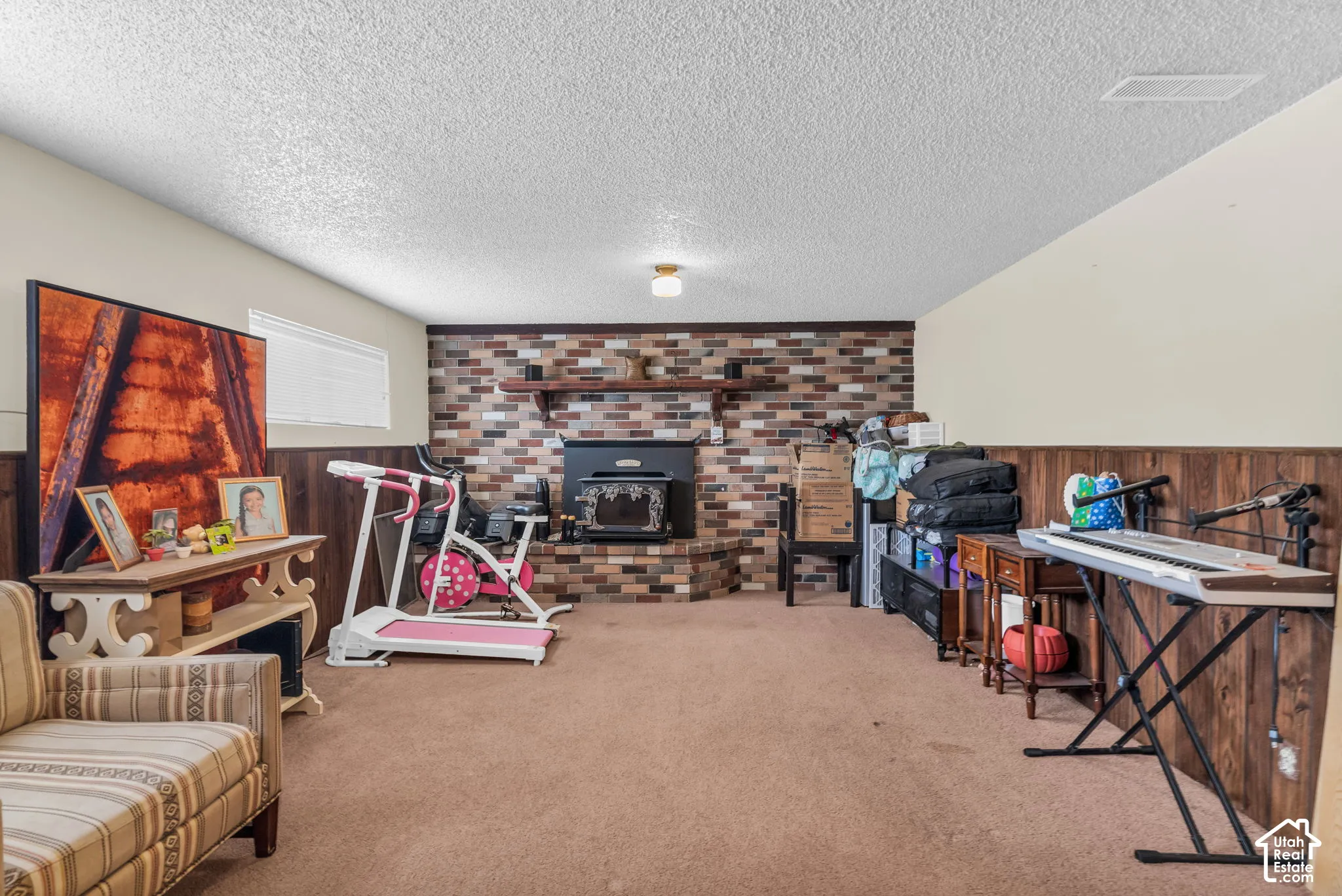 Spacious room featuring a brick-style fireplace surround with a dark-toned wood-burning stove insert