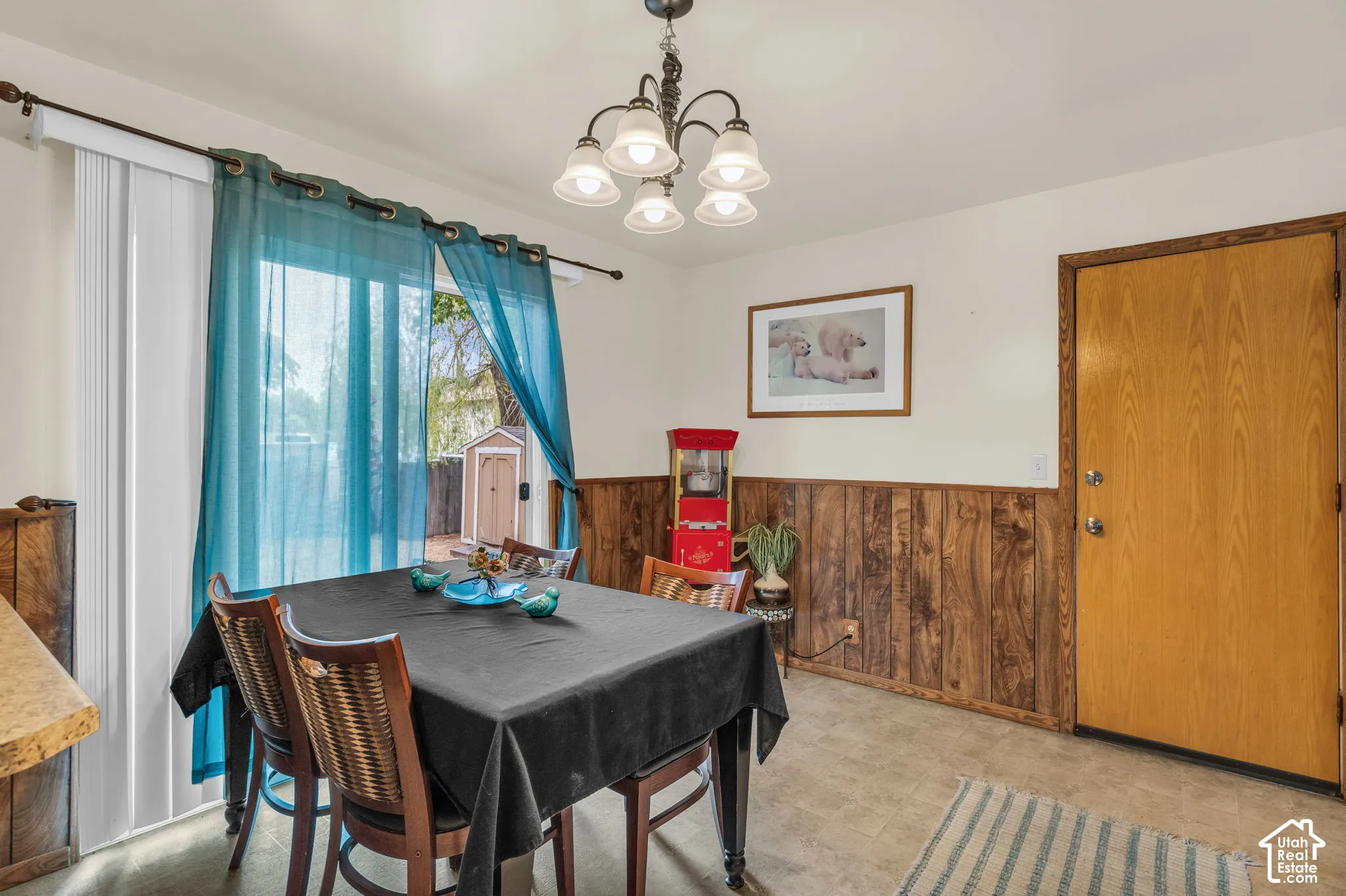 Dining area featuring wood-finish wainscoting, a light-colored door, and a sliding glass door