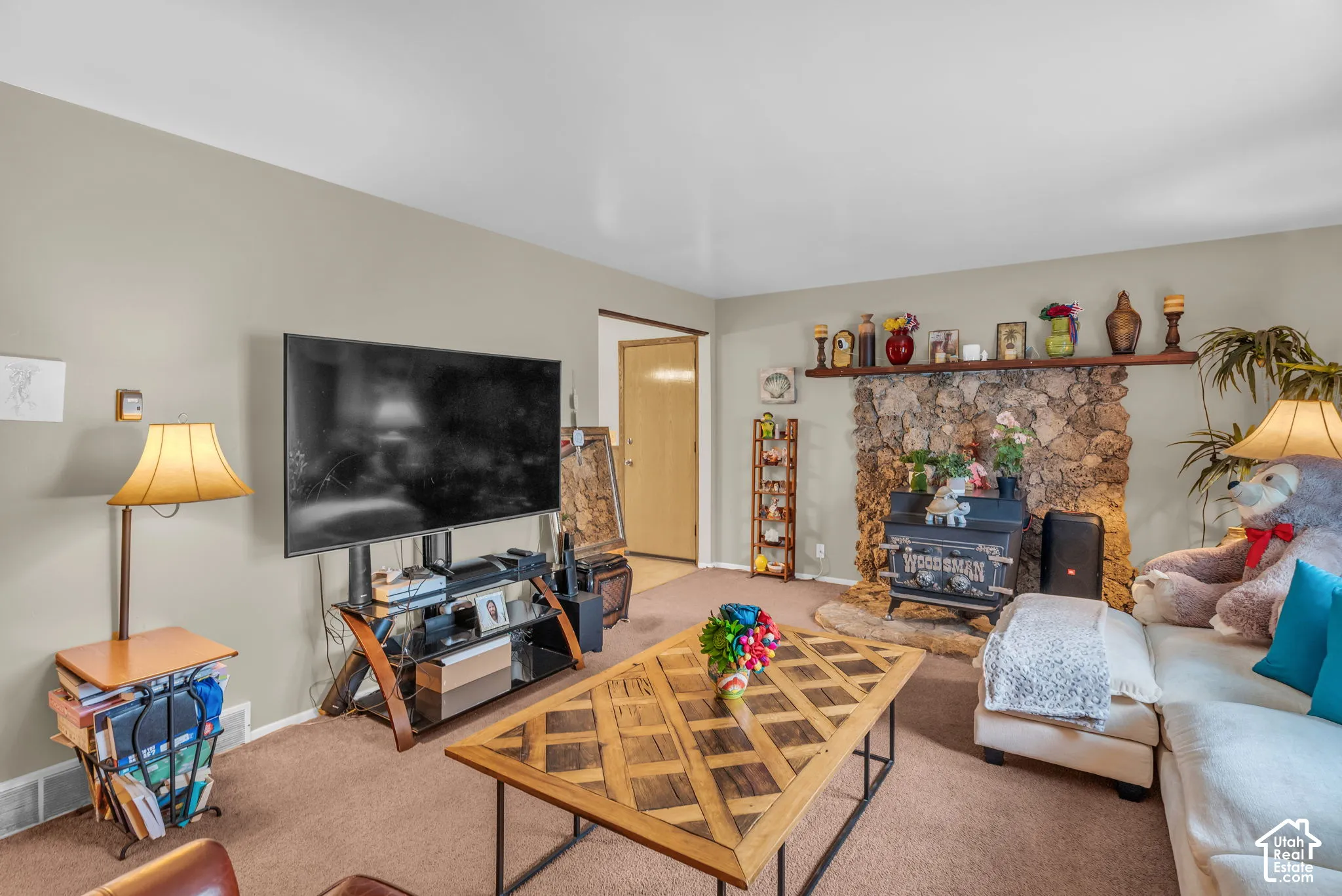 Living area featuring a stone fireplace with a wood-burning insert, a wood mantel, and neutral wall paint