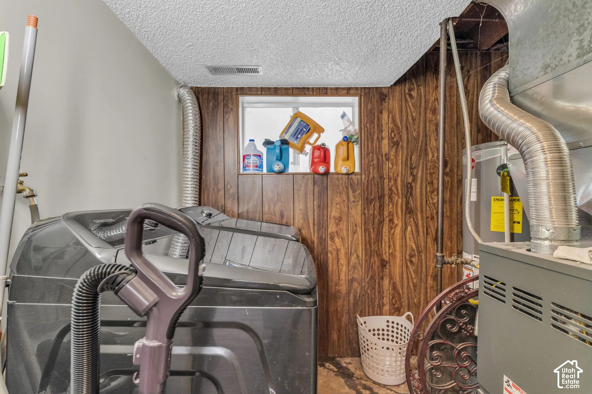 Utility area featuring wood-finish wall paneling, a small window, and a built-in furnace