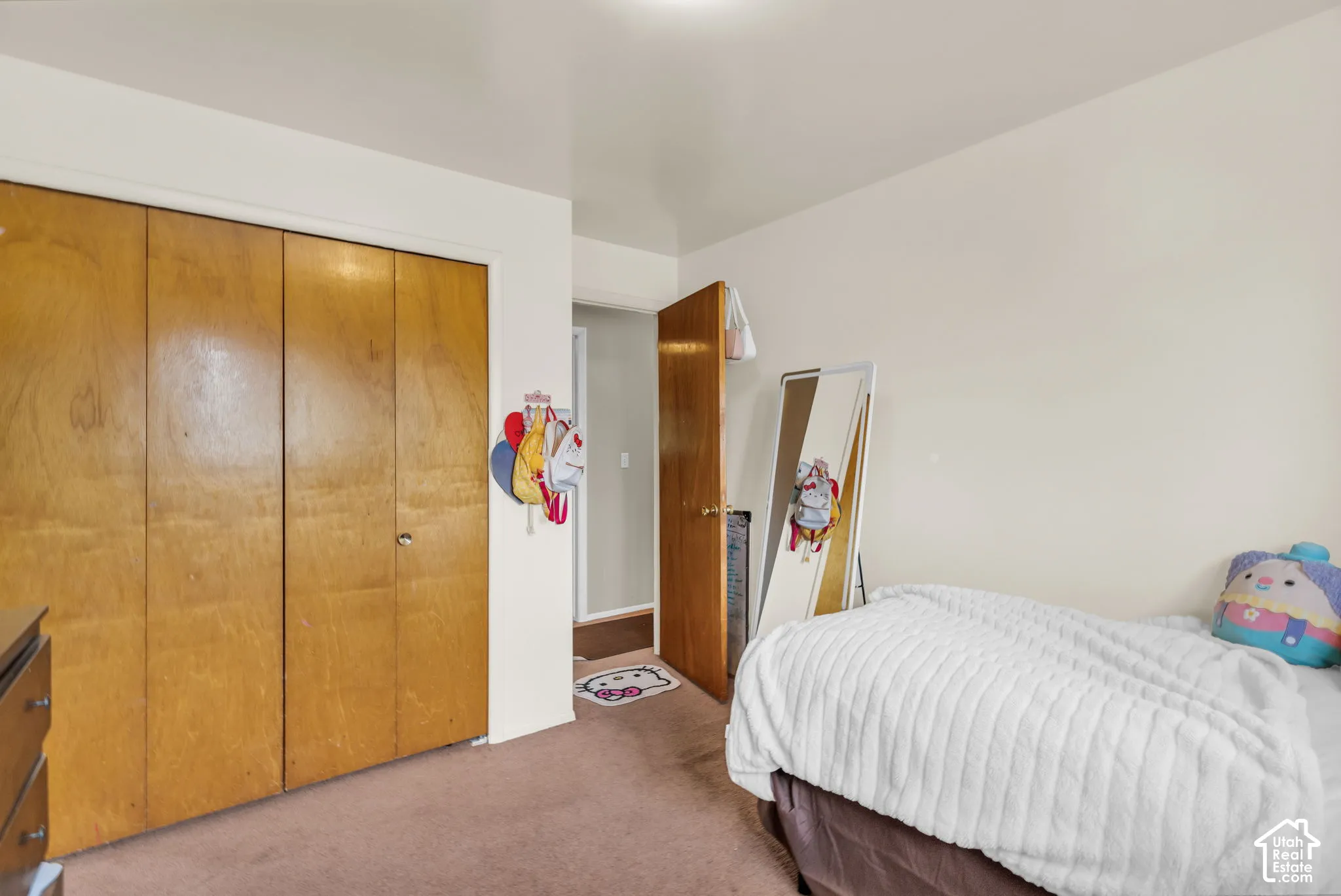 Bedroom featuring wood bi-fold closet doors, cream-painted walls, and brown carpet flooring