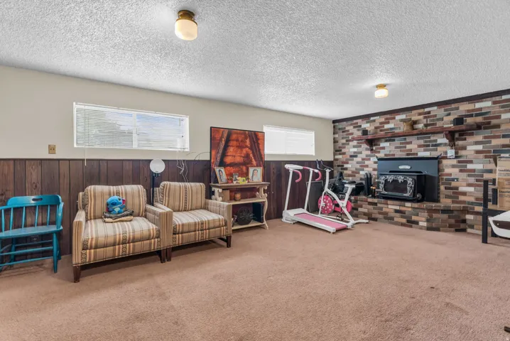 Recreation room featuring a brick accent wall with a built-in fireplace, wood paneling, and a neutral carpeted floor