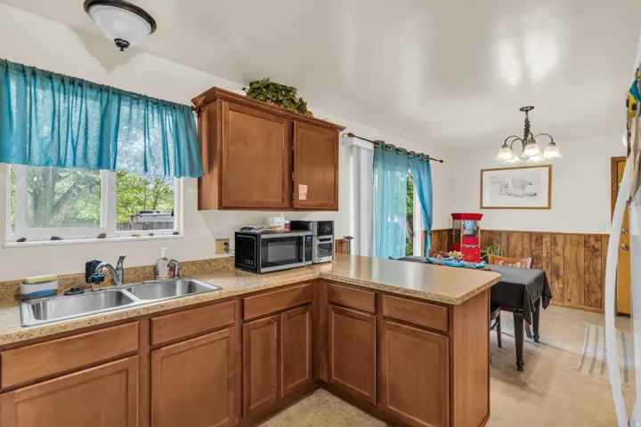 Kitchen featuring wood-finish cabinetry, a double basin stainless steel sink, and a light-toned countertop