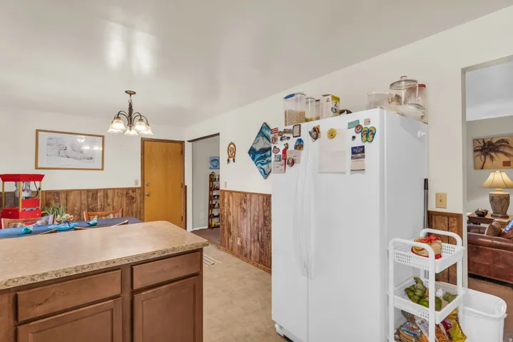Kitchen area featuring a wood-finish island with a stone-finish countertop, wood paneling, and a four-light chandelier