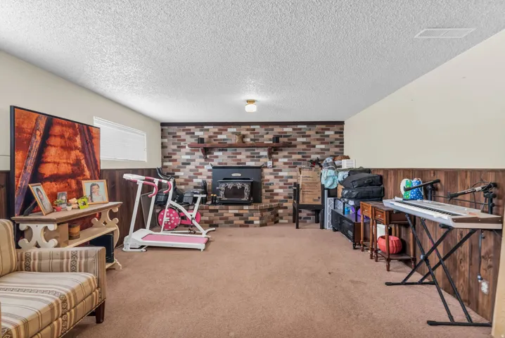Spacious room featuring a brick-style fireplace surround with a dark-toned wood-burning stove insert