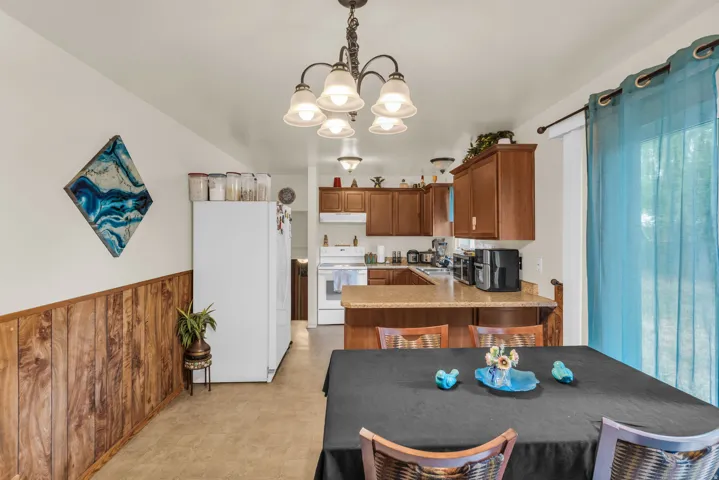 Kitchen and dining area featuring wood-finish cabinetry, a built-in kitchen island with countertop, and wood-finish wall paneling