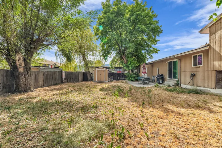 Spacious backyard featuring mature trees and a wood privacy fence