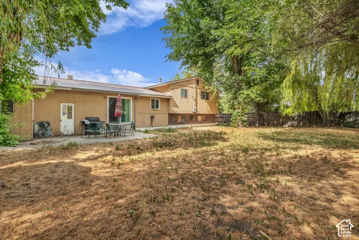Expansive backyard featuring mature trees, a privacy fence, and a concrete patio