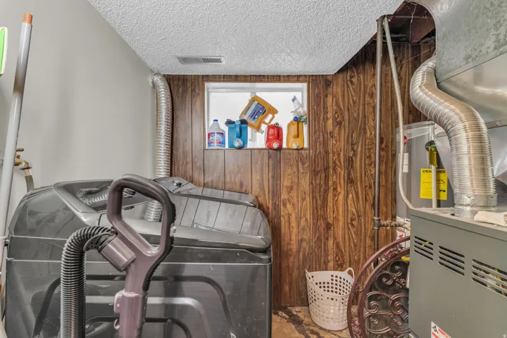 Utility area featuring wood-finish wall paneling, a small window, and a built-in furnace
