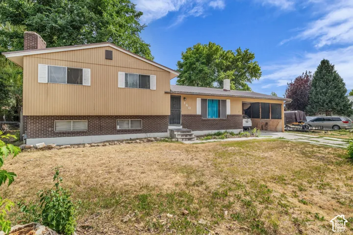 Split-level residence featuring a brick and siding exterior, front lawn, and concrete driveway
